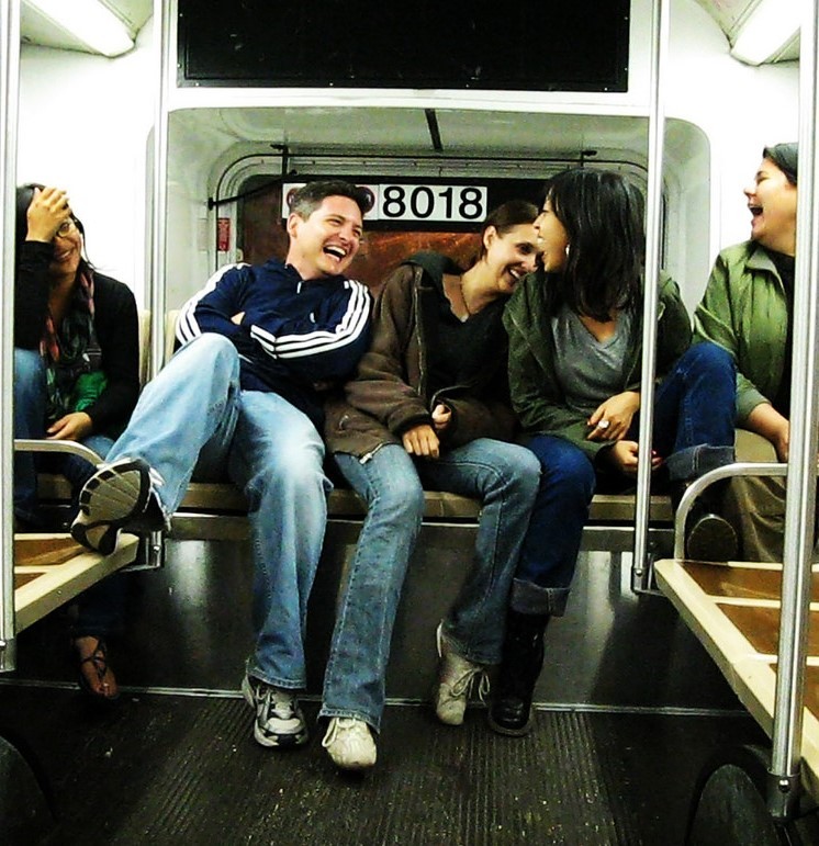 A group of friends sit in the back of a bus laughing together. A group of friends sit in the back of a bus laughing together.