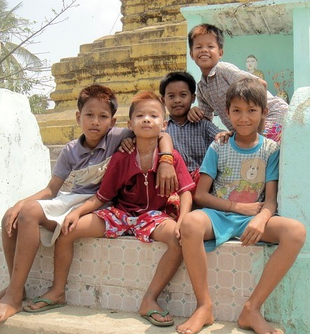 A group of young boys sit together on the steps with their arms around one another. A group of young boys sit together on the steps with their arms around one another.