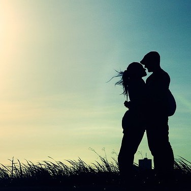 A silhouette of a couple embracing seen against the evening sky. A silhouette of a couple embracing seen against the evening sky.