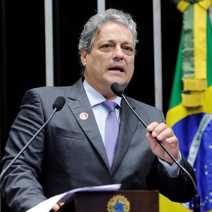 A politician stands behind a lectern and microphone making a speech. A politician stands behind a lectern and microphone making a speech.