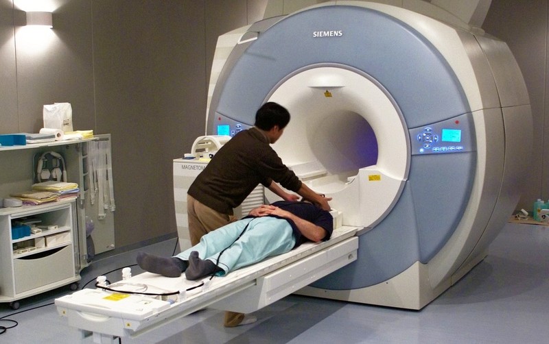 A researcher is preparing to secure the head coil over a participant going into an MRI machine. A researcher is preparing to secure the head coil over a participant going into an MRI machine.