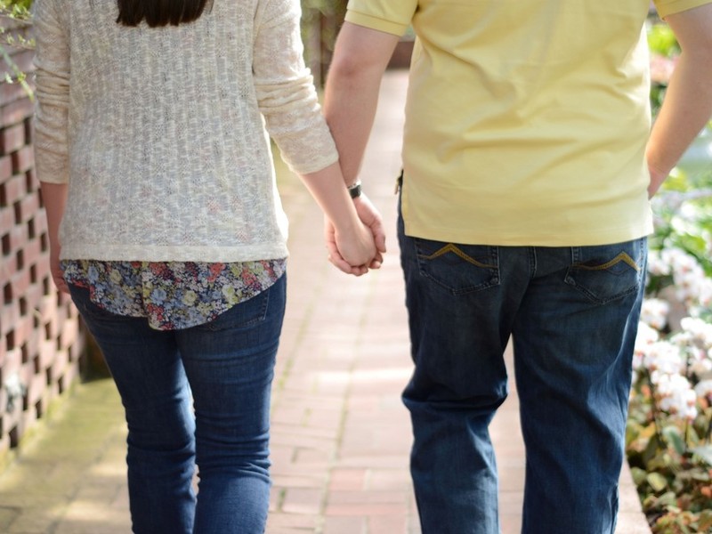 A couple holding hands as they walk down the sidewalk. A couple holding hands as they walk down the sidewalk.