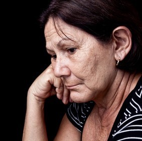 An older woman rests her head on her hand with a sad look on her face. An older woman rests her head on her hand with a sad look on her face.