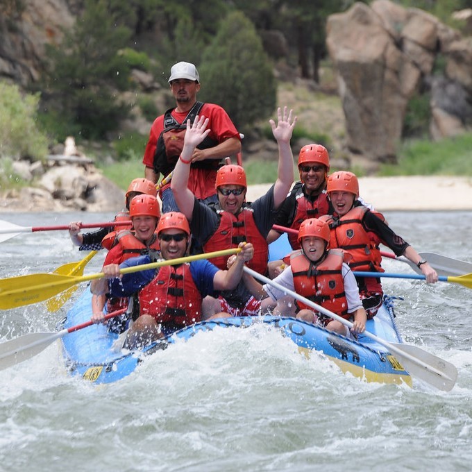 A group of white water rafters paddle together in rough waters. A group of white water rafters paddle together in rough waters.