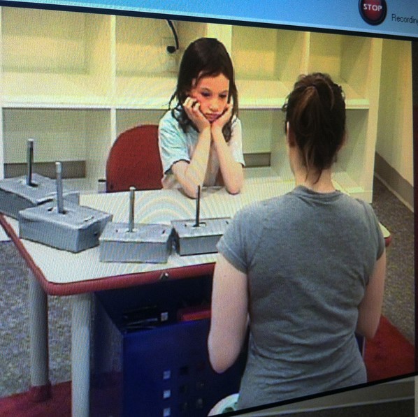 An experimenter sits at a table across from a young girl who is a participant in a laboratory experiment. An experimenter sits at a table across from a young girl who is a participant in a laboratory experiment.