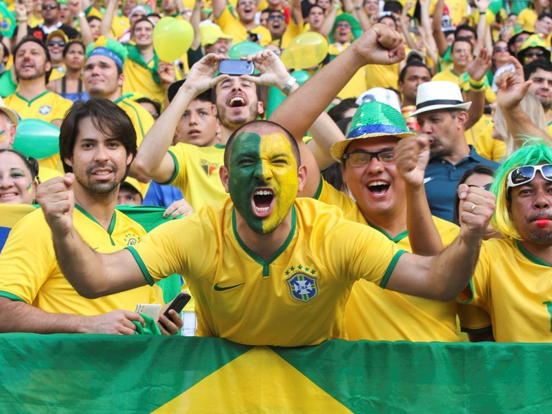 Brazilian soccer fans dressed in the colors of the national team cheer wildly from the stands during a match. Brazilian soccer fans dressed in the colors of the national team cheer wildly from the stands during a match.