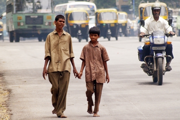 Two boys walk together down a busy street in Bangalore, India while holding hands. Two boys walk together down a busy street in Bangalore, India while holding hands.