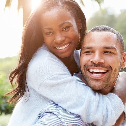 A man holds his partner on his back as she embraces him around the neck. A man holds his partner on his back as she embraces him around the neck.