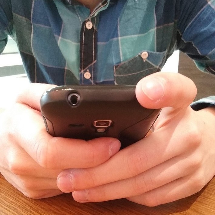 Person seated at a desk using a smartphone. Person seated at a desk using a smartphone.