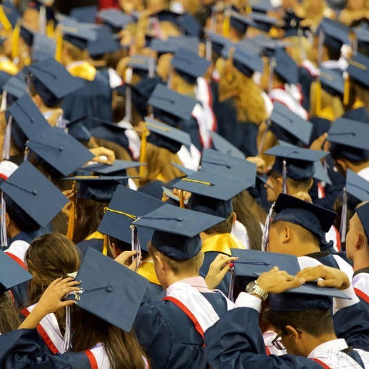 College graduates stand in caps and gowns during a commencement ceremony. College graduates stand in caps and gowns during a commencement ceremony.