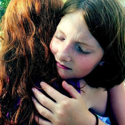 A girl closes her eyes as she hugs her friend. A girl closes her eyes as she hugs her friend.