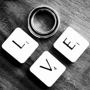 Scrabble tiles and wedding rings spell out the word "Love". Scrabble tiles and wedding rings spell out the word "Love".