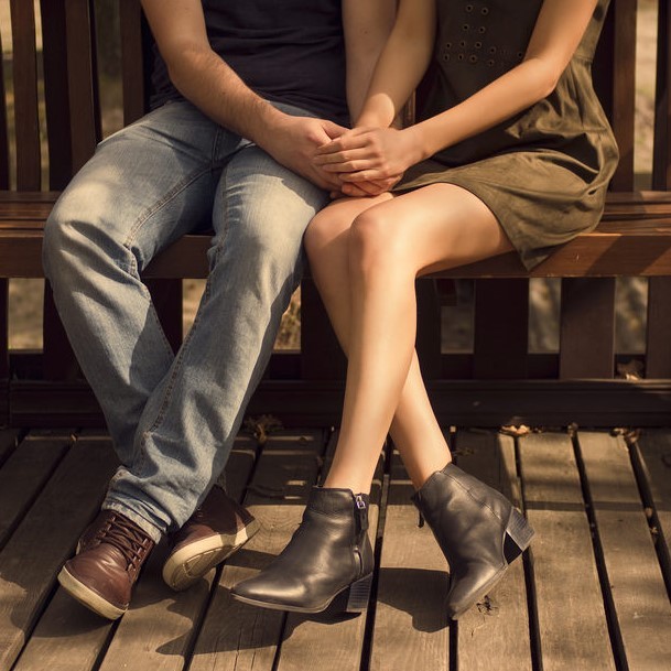 A couple holding hands on a bench. A couple holding hands on a bench.